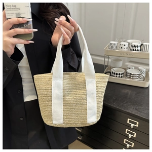Close-up of woven straw tote bag featuring sturdy white canvas handles and fine texture