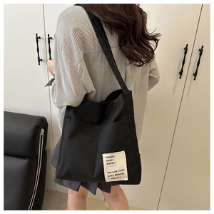 Detail of black canvas tote bag with off-white label and side pocket for daily storage