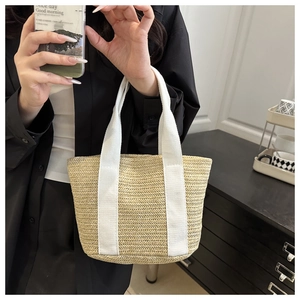Detail of hand-woven beige straw tote bag with wide white fabric shoulder straps