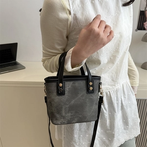 Minimalist vintage grey bucket bag with black leather handle shown on model in studio