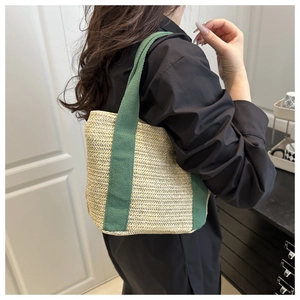 Detail of woven straw tote bag with durable green canvas handles and chevron texture