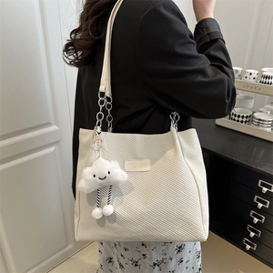 Large beige corduroy tote bag with silver chain strap and plush cloud charm on a model
