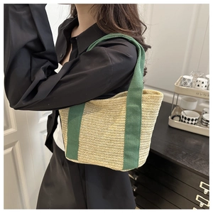 Detail of hand-woven straw tote with contrasting dark green canvas handles