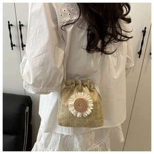Detail of straw woven bucket bag with 3D daisy decoration on white lace dress