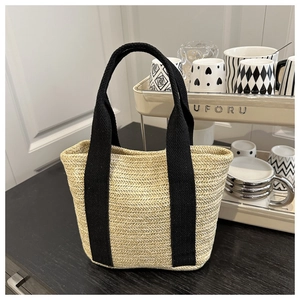 Detail view of V-shaped woven straw tote bag with sturdy black fabric handles