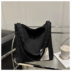 Detail of black canvas tote bag with white Daily Drawing patch and wide handles