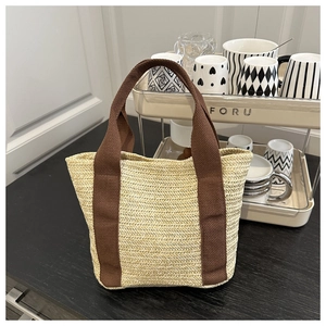 Close-up of woven straw tote bag with brown handles on a minimalist home display