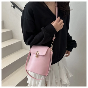 Gros plan d'un sac seau en cuir rose avec une boucle décorative en métal doré en forme de U