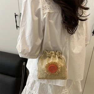 Minimalist straw bucket bag with sunflower applique shown on model's shoulder