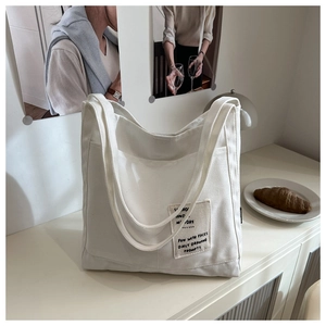 Close-up of cream canvas tote bag with Sunday Monday label on a minimalist desk