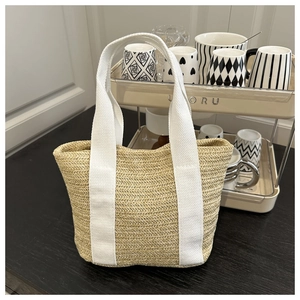 Detail of hand-woven straw tote with white canvas handles and herringbone texture