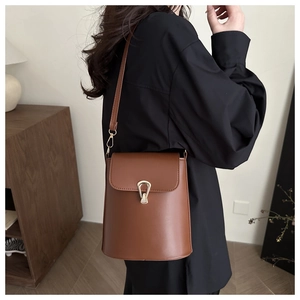 Détail du sac seau en cuir marron avec fermoir doré artistique et bandoulière réglable