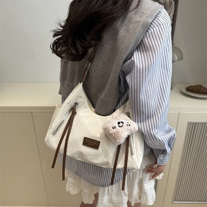 Minimalist beige canvas tote bag with brown leather straps and a cute plush keychain