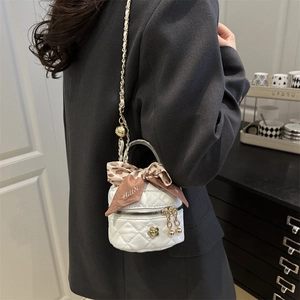 White quilted bucket bag for women featuring silk scarf bow and gold flower badge