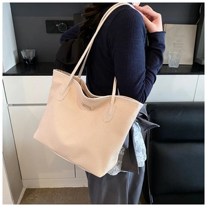Detailed back view of a large cream woven tote bag with slim shoulder straps on a model