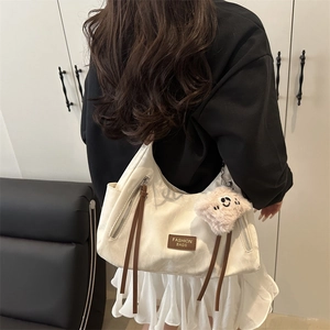 Minimalist beige hobo tote bag with brown leather puller and plush charm on model