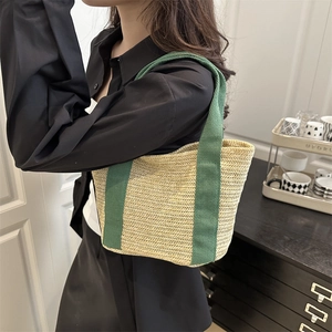 Woven tote bag with green canvas straps and natural beige herringbone pattern