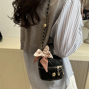 Quilted black mini bucket bag with chain strap and flower charm shown on model