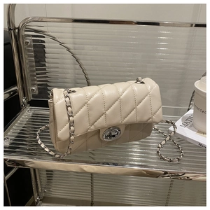 Détail du sac beige matelassé avec chaîne et fermoir rotatif argenté élégant