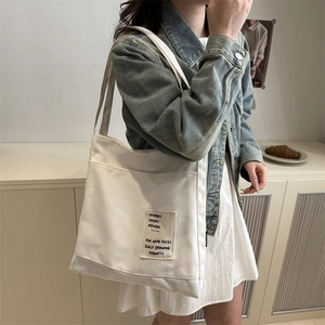 Minimalist white canvas tote bag with black typography pocket detail for casual daily use