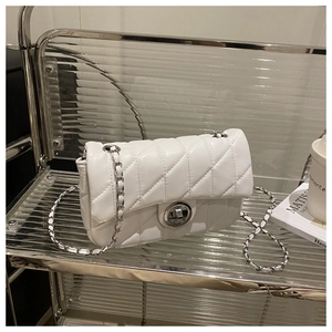 Détail du sac à rabat en cuir matelassé blanc avec chaîne argentée et fermoir rotatif