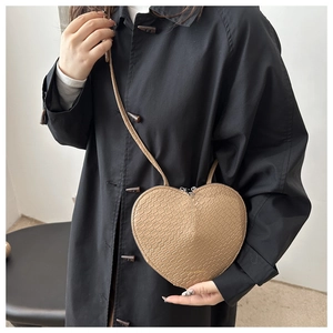 Détail du sac à bandoulière en forme de cœur avec motif crocodile et double fermeture
