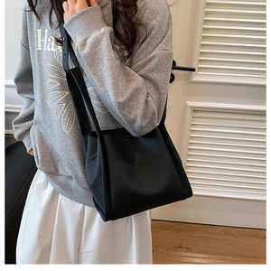 Detail shot of black litchi pattern bucket bag with Fashion embossed logo and slim strap