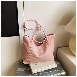 Detailed close-up of pink woven texture and small metal plaque on a chic tote bag