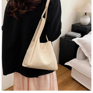 Detail of cream beige bucket bag with litchi texture and Fashion embossed lettering