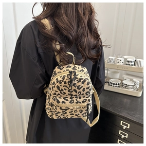 Detail view of mini leopard print corduroy backpack with wide beige straps on a model