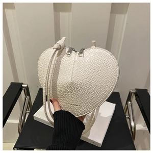 Détail du sac à main blanc en forme de cœur avec texture crocodile et logo mode