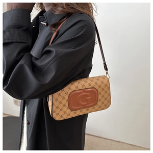 Detail of retro patterned shoulder bag with embossed letter G and brown leather strap