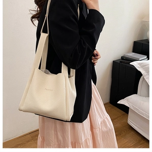 Close-up of cream-colored bucket bag in litchi grain leather with Fashion embroidery