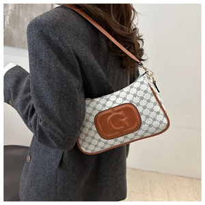 Detail of the white shoulder bag with black diamond pattern and brown G logo patch