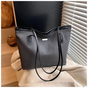 Close-up of dark grey woven tote bag featuring black leather straps and metal hardware