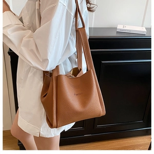 Detail of brown litchi pattern leather shoulder bag with embossed Fashion lettering