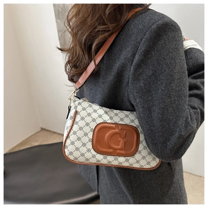 Detailed view of checkered hobo bag featuring brown leather trim and golden hardware