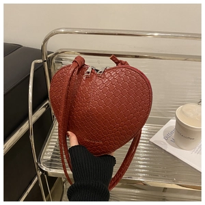 Detailed close-up of reddish-brown heart-shaped bag with woven texture and silver zipper