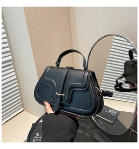 Detail der schwarzen Handtasche mit Litschi-Struktur und eleganter goldener Ringschnalle