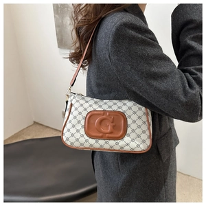 Detail showing white geometric pattern bag with brown leather G logo patch and shoulder strap