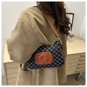 Close-up of retro printed shoulder bag with adjustable brown strap on camel coat