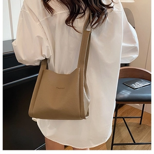 Detail of taupe litchi grain leather bucket bag featuring a Fashion embossed logo