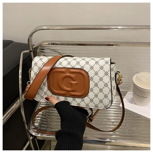 Detail of white diamond pattern shoulder bag with brown G logo on a silver shelf