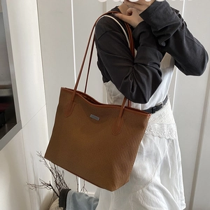 Brown woven tote bag with a minimalist metal plaque and slender shoulder straps