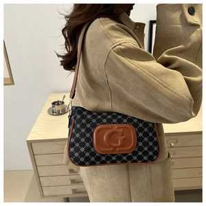 Detail of a vintage-style plaid baguette bag worn with a chic camel wool coat
