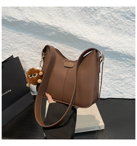 Vue détaillée du sac seau en cuir marron avec boucle dorée et pendentif en peluche doux