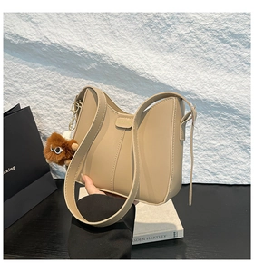 Détail du sac seau en cuir PU beige avec étiquette mode et breloque en peluche drôle