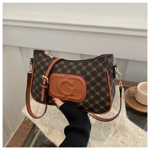 Close-up of retro brown monogram shoulder bag featuring leather G logo and gold zipper