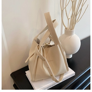 Close-up of cream litchi grain leather bucket bag with fashion embossed text and strap