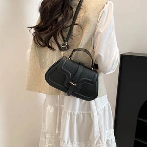 Minimalistische schwarze Umhängetasche mit Goldschnalle an Model im Spitzenkleid